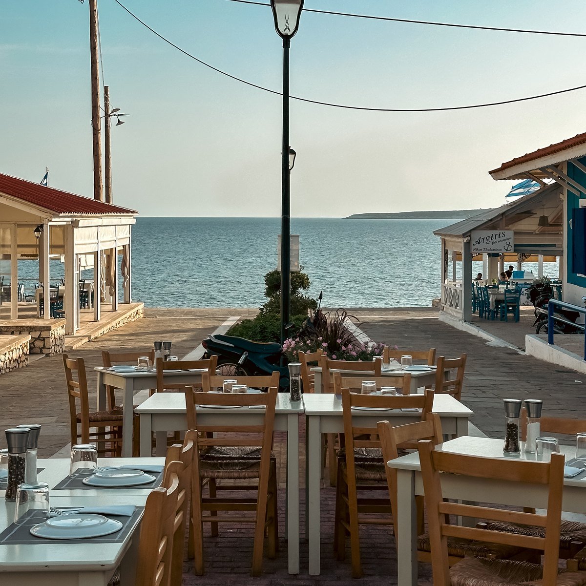Tables laid along the seafront at Marathopoli, looking out to Proti islet