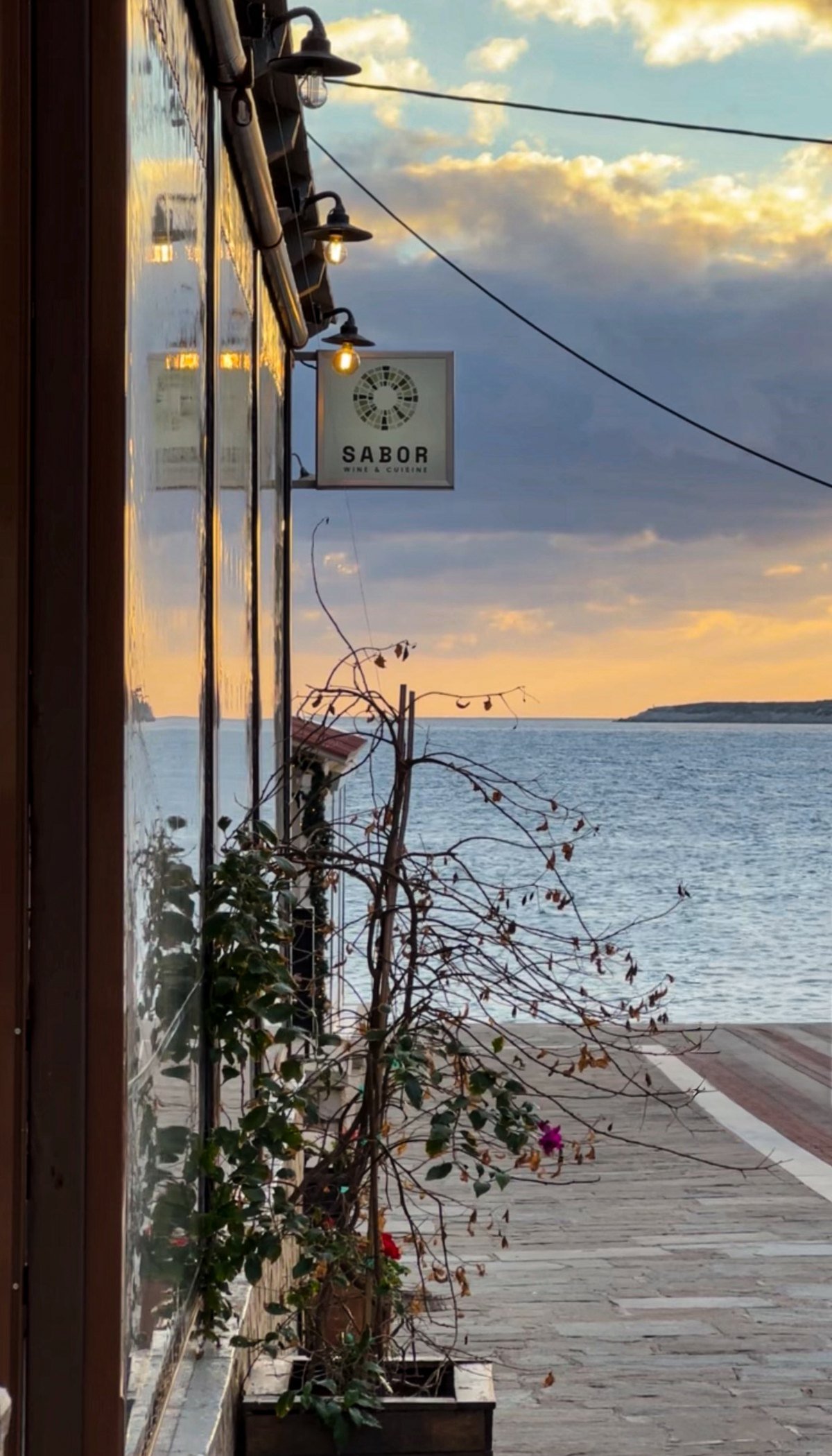The SABOR sign on the pedestrian street at sunset, the sea and Proti beyond
