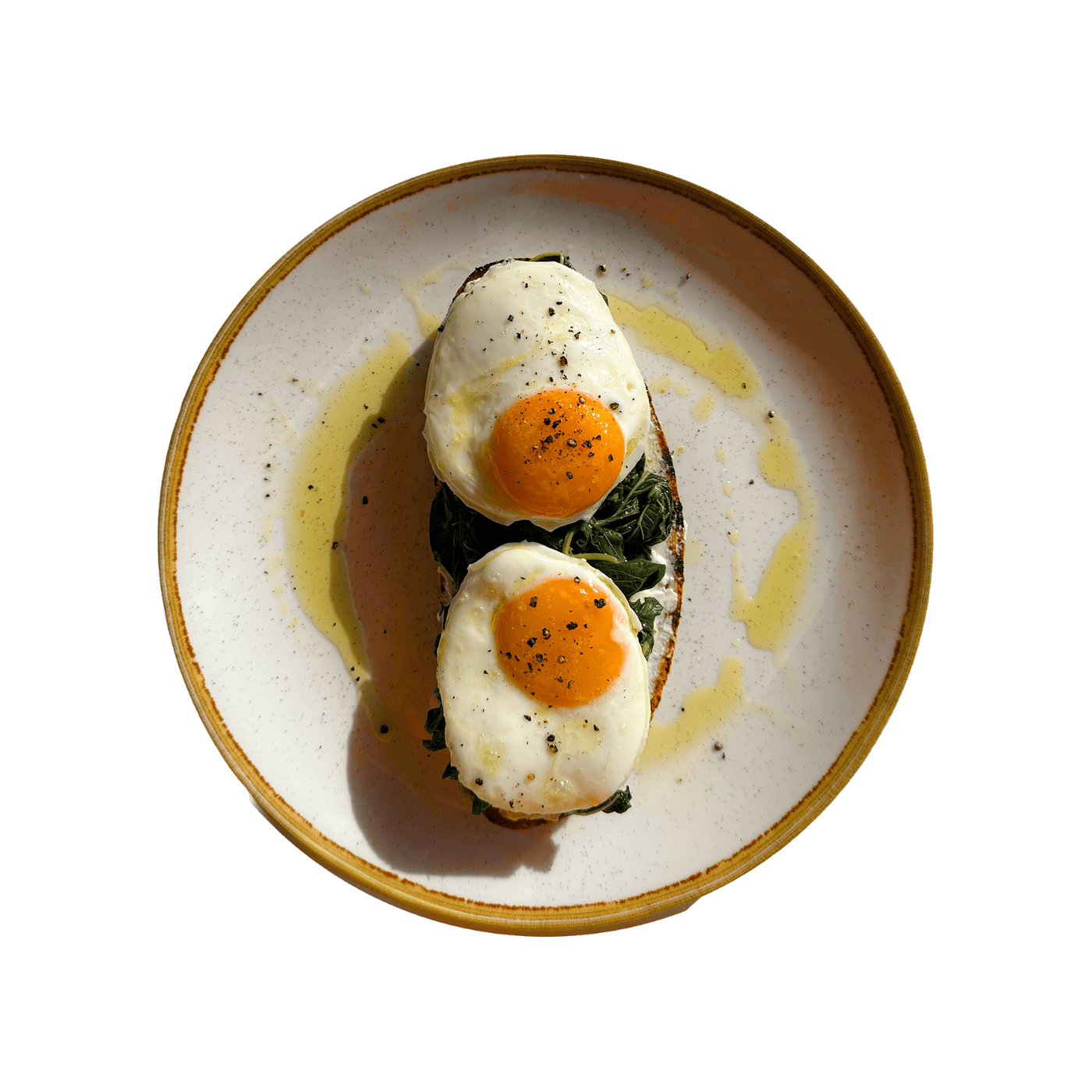 Two fried eggs and wild greens on sourdough with feta cream and olive oil